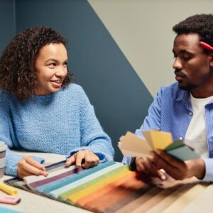 Smiling Female Designer Working with Colleague Selecting Color of Fabric at Table